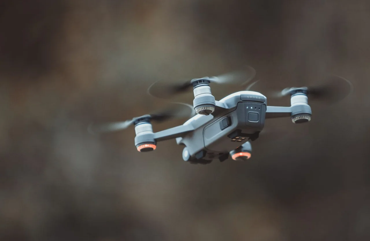 Compact camera drone in flight against a softly blurred landscape