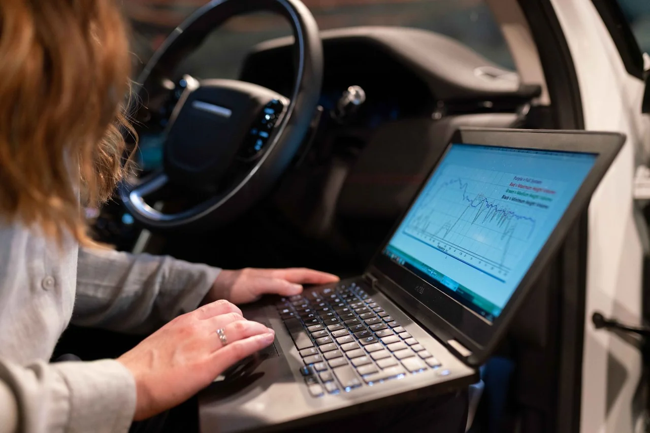 Engineer analysing vehicle measurements on a laptop inside a car